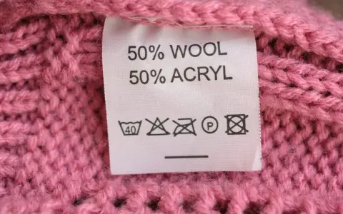 Tvättråd på en rosa stickad tröja: 50% ull, 50% akryl. Kan indikera nackdelar med ull som känslighet för höga temperaturer.