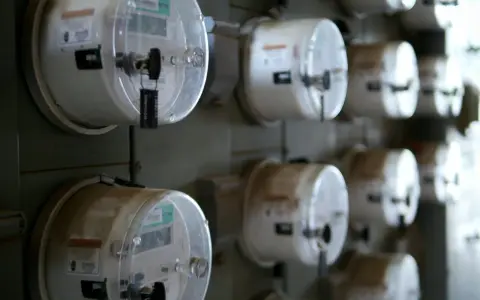 Rząd liczników energii elektrycznej, każdy z plombą. Jeden z nich, jako sprzedawca rezerwowy, jest widoczny z bliska.
