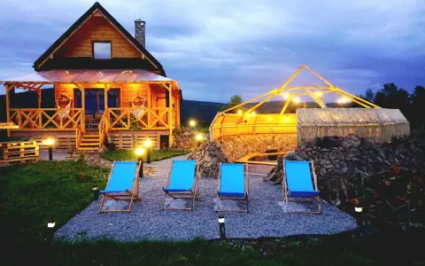 Drewniany domek z werandą, jacuzzi pod zadaszeniem i leżakami w malowniczej okolicy.