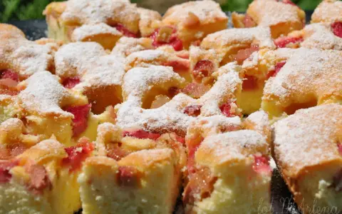 Pyszne ciasto z rabarbarem, pokrojone na kwadraty i posypane cukrem pudrem. Idealne na letnie popołudnie.