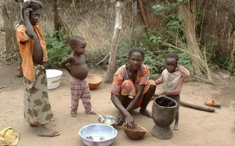 Dzieci i matka w tradycyjnej chacie w Burkina Faso. Kobieta przygotowuje posiłek, a dzieci obserwują.