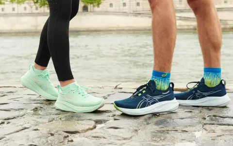 Två par löparskor, mintgröna Asics Gel Luminus 2 dam och mörkblå herrskor, står på stenar vid en flod.