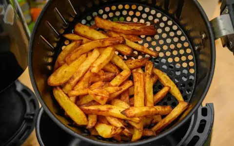 Złociste frytki w koszyku frytkownicy beztłuszczowej. Tak działa air fryer, przygotowując chrupiące przekąski.