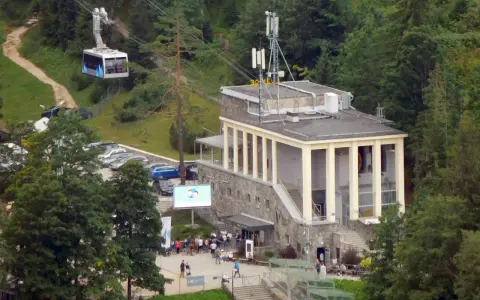 Kolejka linowa nad budynkiem stacji PKL na Kasprowym Wierchu, z widocznymi samochodami i ludźmi.