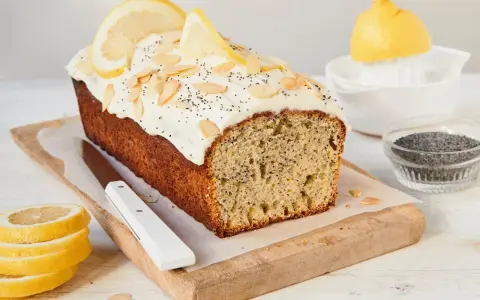 Saftiger zitronenkuchen mit mohn, garniert mit Mandelsplittern und Zitronenscheiben.