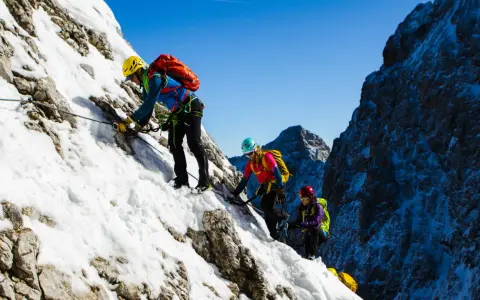 Drei Bergsteiger meistern den Klettersteig Zugspitze im Schnee.