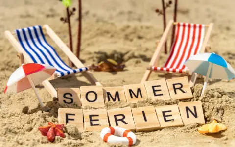 Strandkörbchen, Palmen und die Worte "Sommerferien" im Sand. Perfekt für die Sommerferien in Brandenburg!