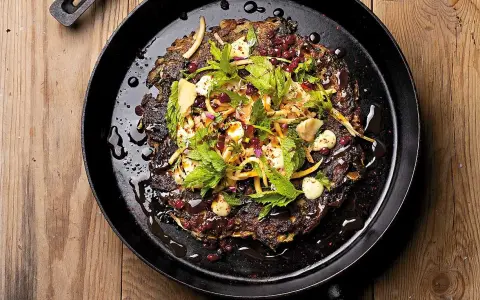En mörk, krispig pannkaka med kirskål, toppad med färska örter, granatäppelkärnor och en krämig dressing. Ett spännande kirskål recept!