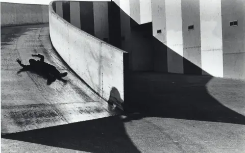 A silhouetted figure lies on a curved concrete ramp, arms outstretched, at the Janet Borden Gallery.