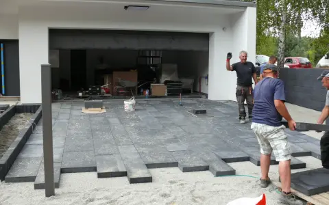 Pracownicy układają betonowe płyty, tworząc nowoczesny podjazd. Wygląda na to, że beton zamiast kostki to nowy trend.