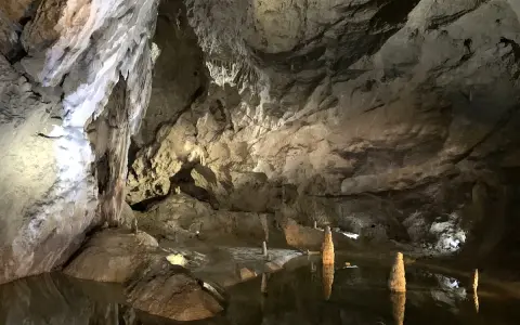 Wnętrze jaskini Bielskiej z wodą i stalagmitami.