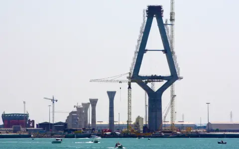 Construcción de un puente con pilares de hormigón y grúas, sobre el mar.