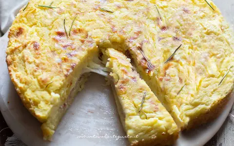 Una fetta di torta di patate filante, dorata e profumata al rosmarino, pronta per essere gustata.