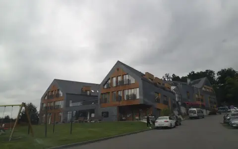 Nowoczesny hotel z drewnianymi elementami i kamienną elewacją. Na trawniku plac zabaw. Wiele pozytywnych osada-sniezka opinie potwierdza jego urok.