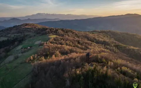 Wieża widokowa w Beskidzie Sądeckim na tle pasm górskich o zachodzie słońca.