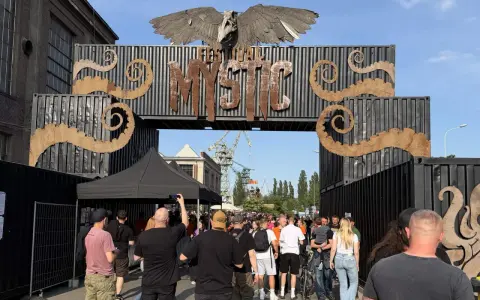 Tłum ludzi wchodzi przez bramę festiwalową "Mystic". To jedno z wielu wydarzeń kulturalnych, takich jak festiwale filmowe w Polsce.
