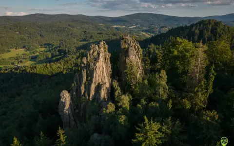Skaliste szczyty, jak sokolik duży, górują nad lasem. Na jednym z nich platforma widokowa z turystą.