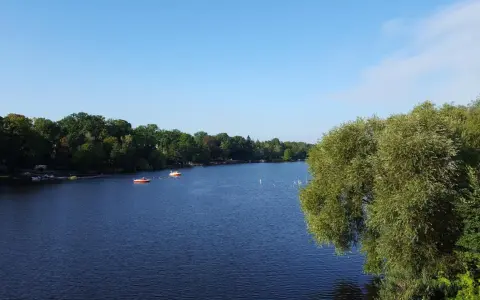 Ein ruhiger See mit Booten, umgeben von grünen Bäumen. Ein perfekter Ort für einen entspannten Tag, ein echter Geheimtipp in Berlin.