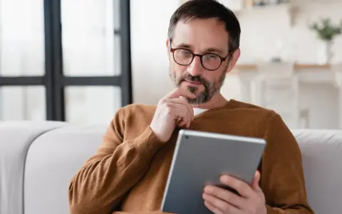 Mann sitzt nachdenklich auf Sofa, sein Samsung Tablet geht nicht mehr an.