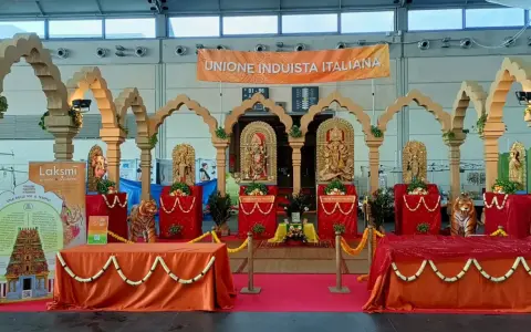 Allestimento per il festival dell'oriente Rimini con statue induiste, archi in legno e un grande striscione "Unione Induista Italiana".