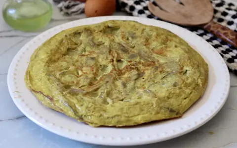 Frittata di carciofi dorata e soffice su un piatto bianco, pronta per essere gustata.