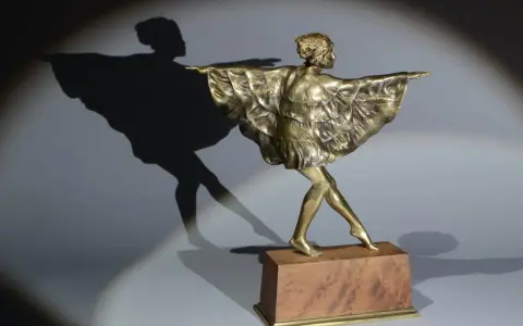 Sculpture en bronze d'une danseuse par Marcel Bouraine, sa robe à volants flottant, projetant une ombre gracieuse.