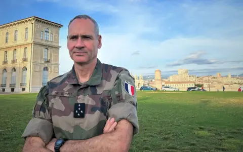 Un officier français, P. Schill, pose devant un bâtiment historique. Comment retrouver un officier ? Il suffit de regarder son uniforme et son insigne.