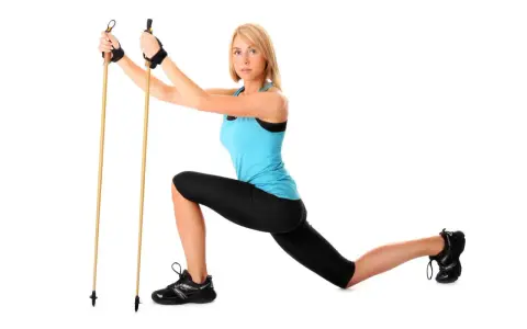 Kobieta w stroju sportowym demonstruje ćwiczenie z kijkami do nordic walking, pokazując, jak ustawić kijki do nordic walking.