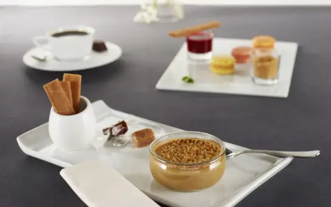Un café gourmand avec diverses mignardises : verrine caramélisée, macarons, biscuits, chocolats. Idéal pour des recettes de mignardises pour café gourmand.