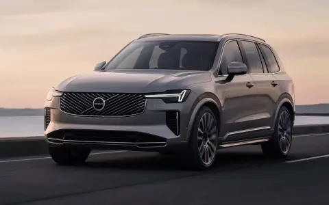 Elegancki, szary Volvo XC90 T8 sunie po drodze przy zachodzie słońca.