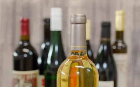 Butelki z winem na tle drewnianej ściany. Zastanawiasz się, ile alkoholu można wziąć do Norwegii samolotem?