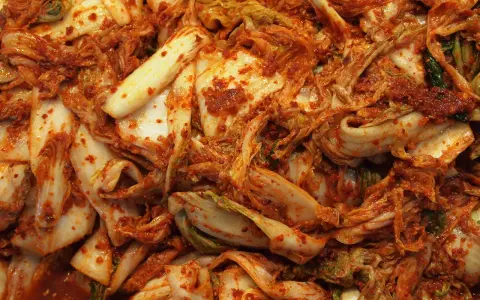 Zbliżenie na świeże, pikantne kimchi z kapusty pekińskiej, pokryte czerwoną pastą chili.