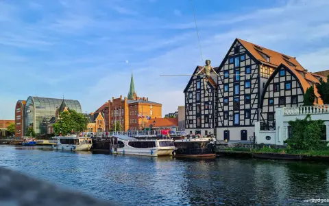 Bydgoszcz atrakcje: rzeka Brda, łodzie, zabytkowa kamienica z postacią na linie i nowoczesny budynek.