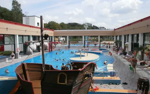 Ein Piratenschiff-Spielplatz in einem Freibad mit vielen Badegästen.