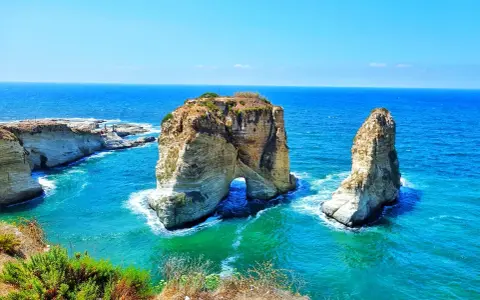 The Raouché sea stacks, iconic natural landmarks and historical sites in Lebanon, stand majestically against the bright blue Mediterranean Sea.