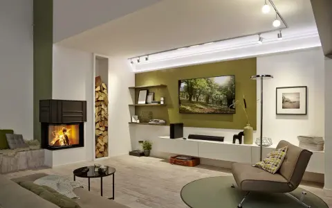 Nowoczesny salon z palącym się kominkiem i telewizorem na jednej ścianie. Obok kominka stos drewna.