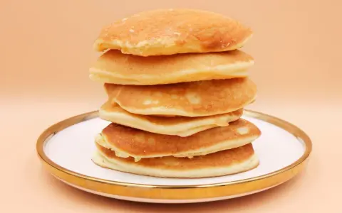 Stos puszystych, złotych pancake'ów na talerzu. Idealny przepis na śniadanie.