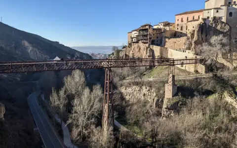 Puentes de Cuenca: una estructura de hierro cruza un barranco, con casas colgando de acantilados rocosos al fondo.