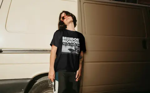 Joven con gafas de sol naranjas y camiseta negra con el diseño "BRANDON MONTOYA NO ES COMO YO".