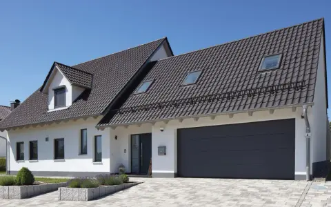 Nowoczesny dom z garażem i ciemnym dachem. Kąt nachylenia dachu 10 stopni zapewnia estetyczny wygląd i dobrą ochronę.