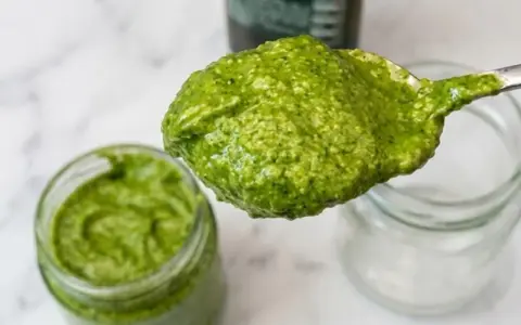 Un cucchiaio di fresco pesto genovese, pronto per essere messo in un vasetto. La ricetta pesto genovese frullatore è facile e veloce.