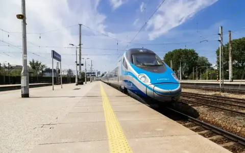 Pendolino na peronie, niebiesko-srebrny pociąg, słoneczny dzień.