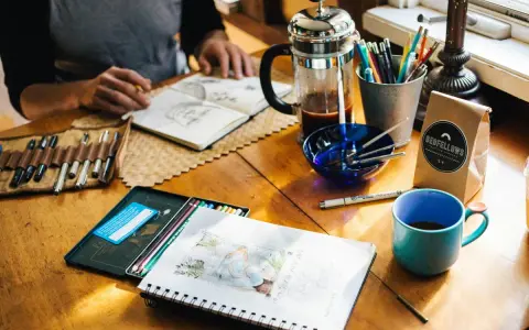 Kreative Inspiration am **cafe impuls**: Skizzenbuch, Stifte, Kaffee und eine Tasse laden zum Malen ein.