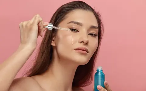 Kobieta aplikuje serum z retinyl palmitate na skórę pod okiem. Błękitna buteleczka kosmetyku w dłoni.