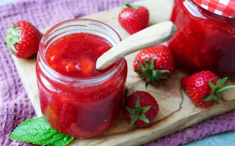 Frische Erdbeeren und selbstgemachte Marmelade in einem Glas. Perfekt zum Marmelade einfrieren für den Winter.