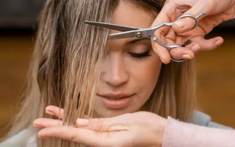 Manos cortando el flequillo de una mujer. Un momento perfecto para saber cuando es mejor cortarse el pelo y renovar tu look.