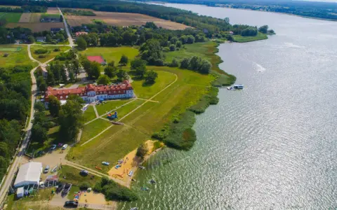 Widok z lotu ptaka na **zalew domaniow** z hotelem, plażą, kajakami i łodziami.