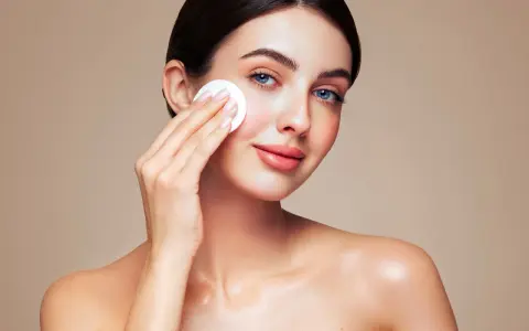 Une femme au maquillage impeccable utilise un coton pour se démaquiller, prouvant que le maquillage n'abîme pas la peau si on en prend soin.
