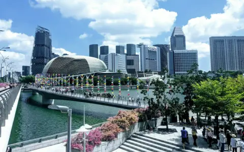 Fakta om Singapore: En bro med flaggor leder mot en futuristisk skyline med Esplanade-teatern.