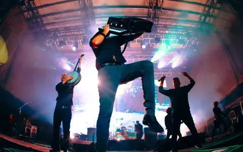 Energetyczne koncerty Dropkick Murphys: muzyk gra na akordeonie, inny na banjo, a w tle wokalista z mikrofonem.